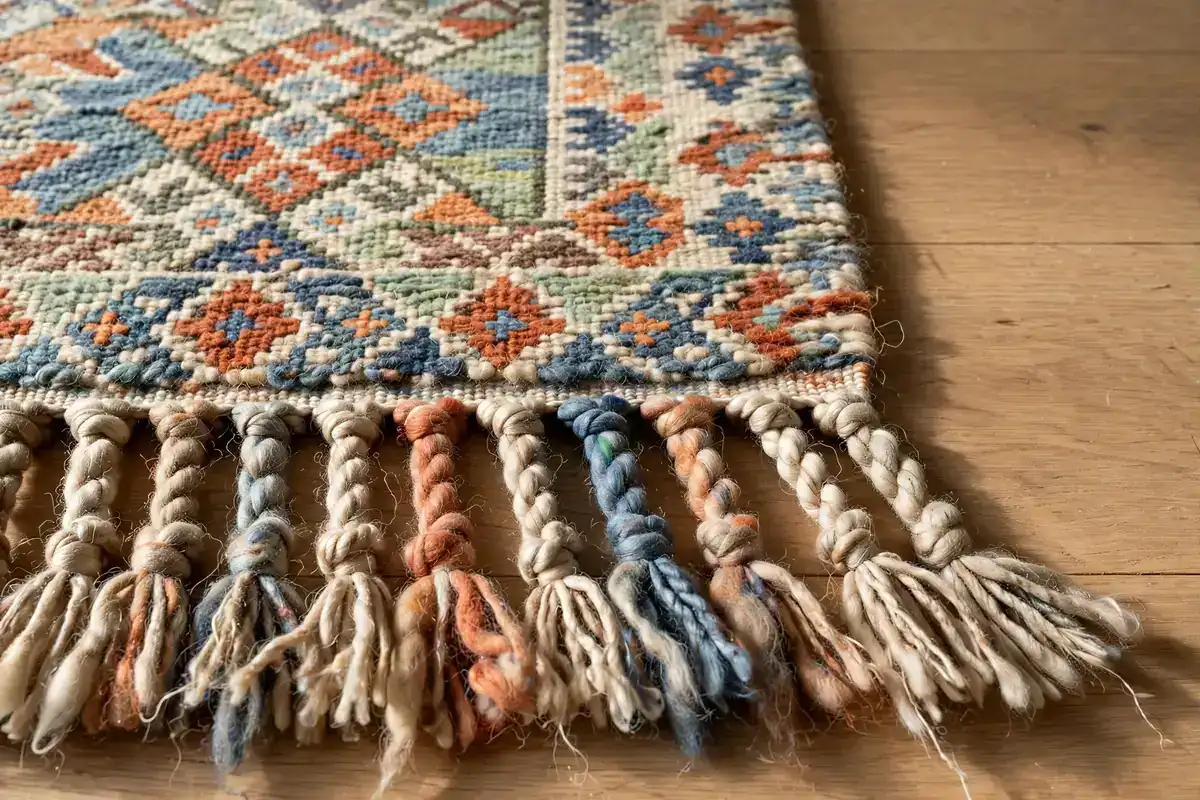 Close-up of the woven fringe and dyed wool pile of a patterned area rug