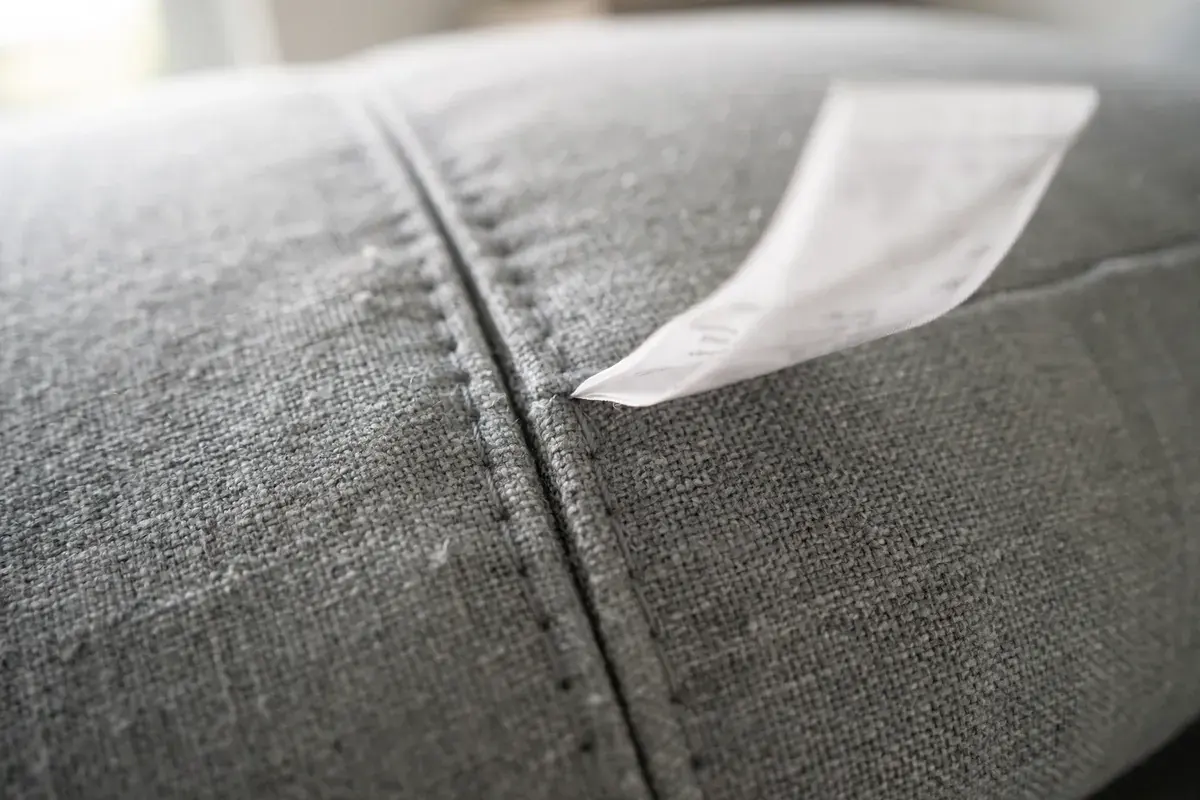 Close-up of a sofa cushion seam with a sewn-in care tag showing fabric weave